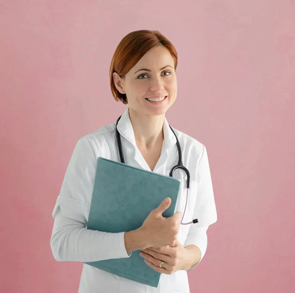 A woman in a white medical coat with a stethoscope around her neck holds a blue folder and smiles, standing against a pink background.